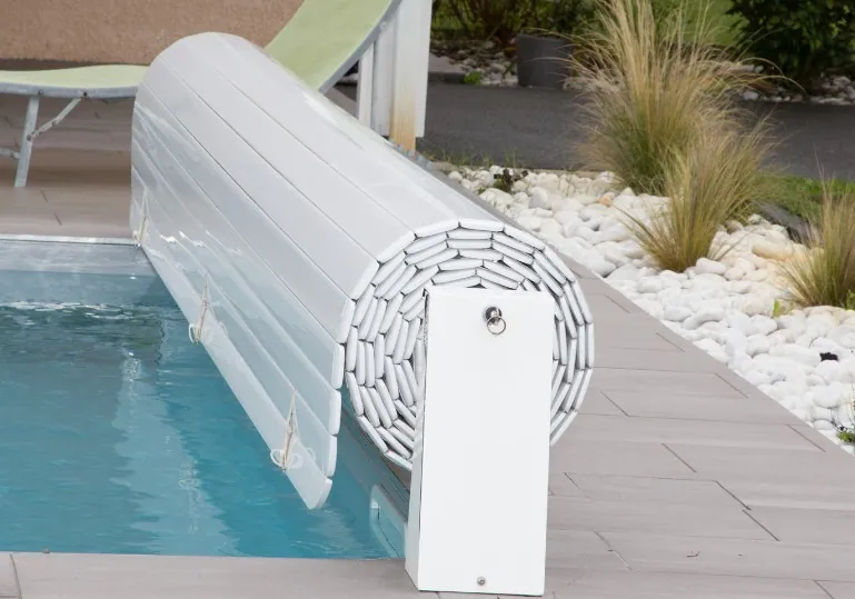 Cubierta de lamas de seguridad para piscina Cubierta de lamas de seguridad enrollada en el borde de una piscina