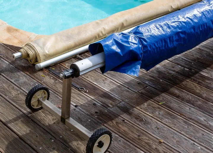 Enrollador con ruedas para manta térmica de piscina sobre tarima de madera