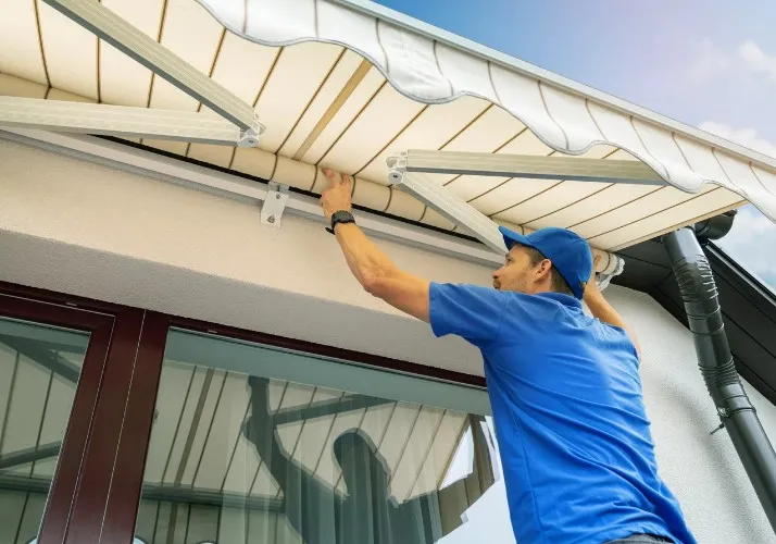 Instalador ajustando los brazos de un toldo en una fachada de Murcia