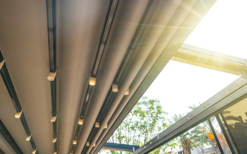 Lona de palillería recogida bajo una pérgola de aluminio con focos integrados en la estructura