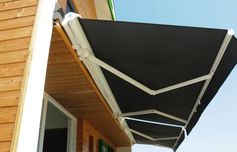 Toldo de brazos articulados con lona negra motorizado en el porche de una vivienda en Murcia