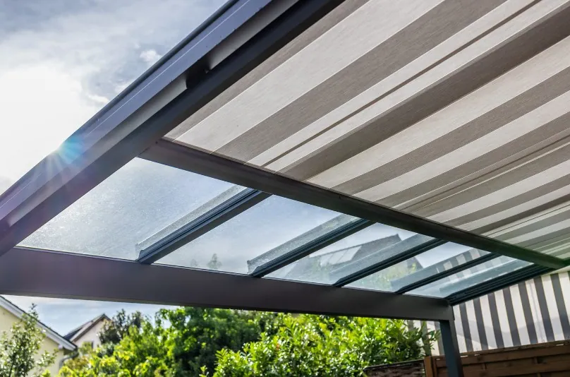 Lona a rayas grises y blancas extendida bajo la cubierta de una pérgola de aluminio