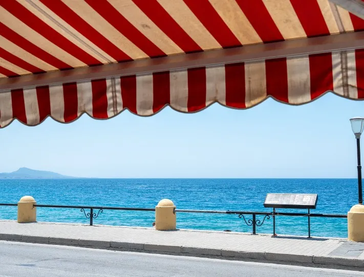 Toldo con lona a rayas rojas en un paseo marítimo de la Región de Murcia