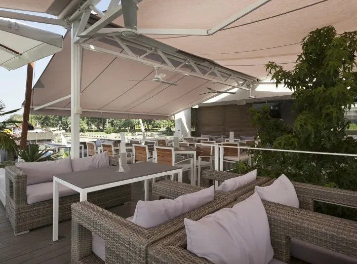 Toldos de brazos extensibles cubriendo una terraza chill out con sofás