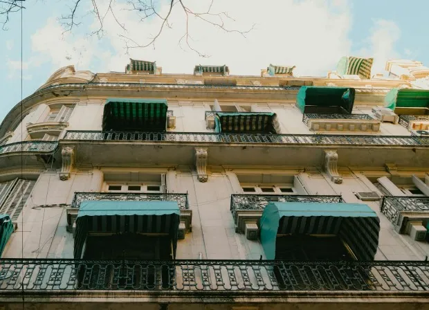 Toldos verdes en balcones de fachada clásica Toldos verdes de brazos, todos iguales, en los balcones de una fachada clásica